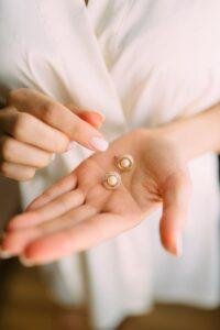 Close-up of elegant pearl earrings held in a hand, showcasing luxury jewelry.