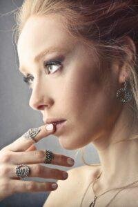 Stylish woman with elegant jewelry admires her reflection, embodying modern beauty.