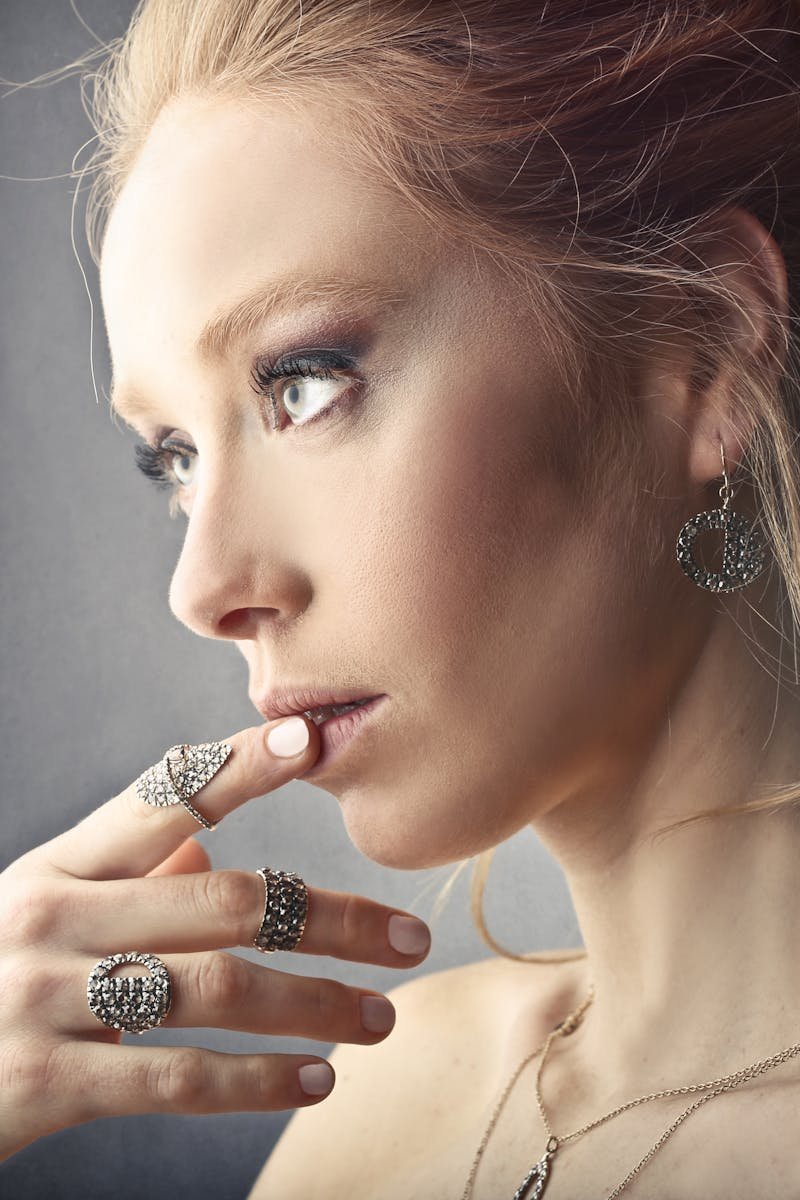 Stylish woman with elegant jewelry admires her reflection, embodying modern beauty.